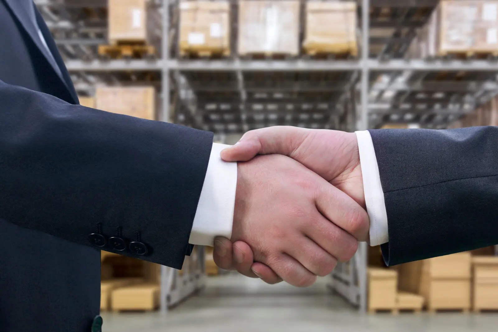 Two men shaking hands in a warehouse.