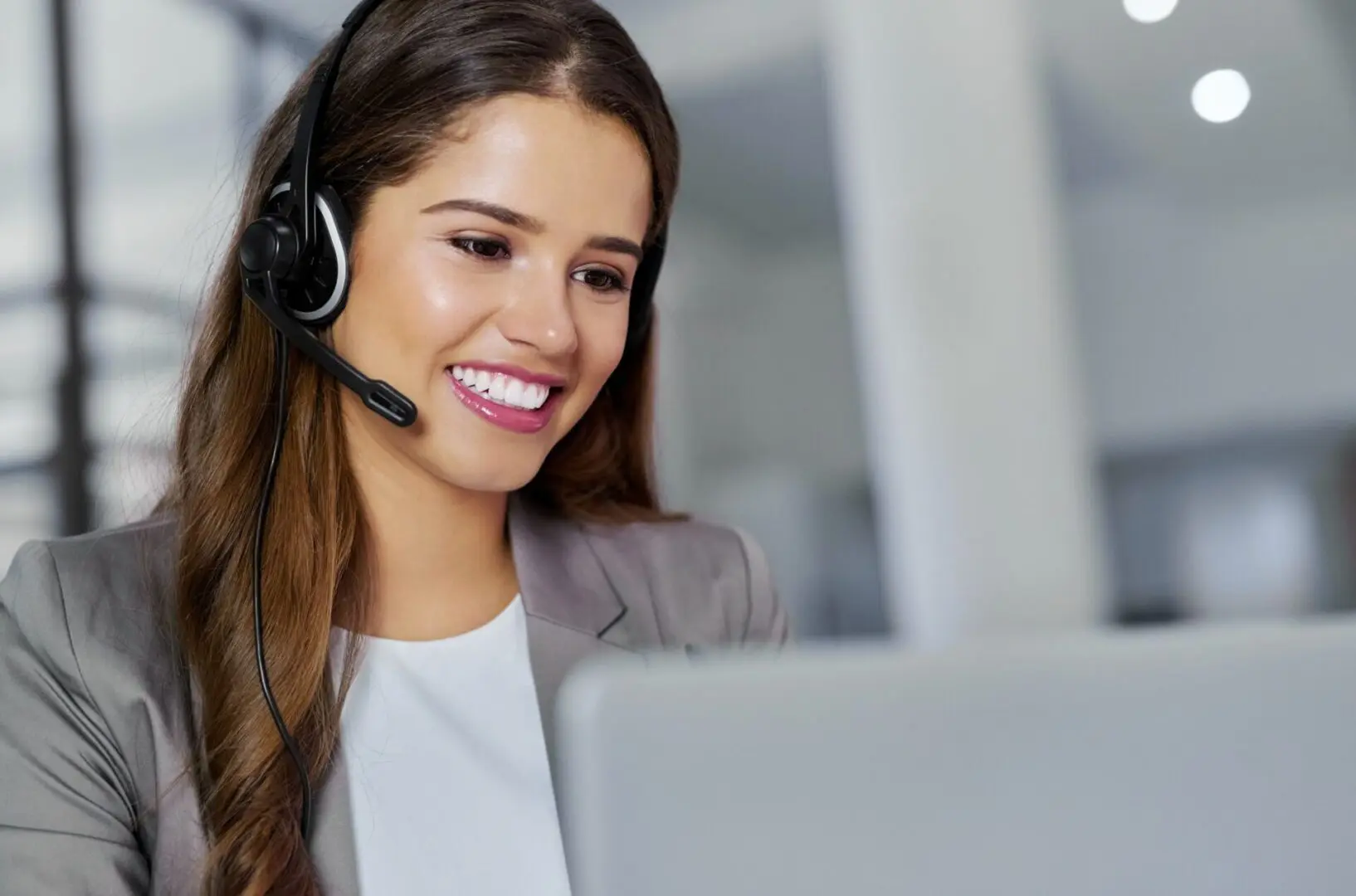 A woman with headphones on looking at her laptop.